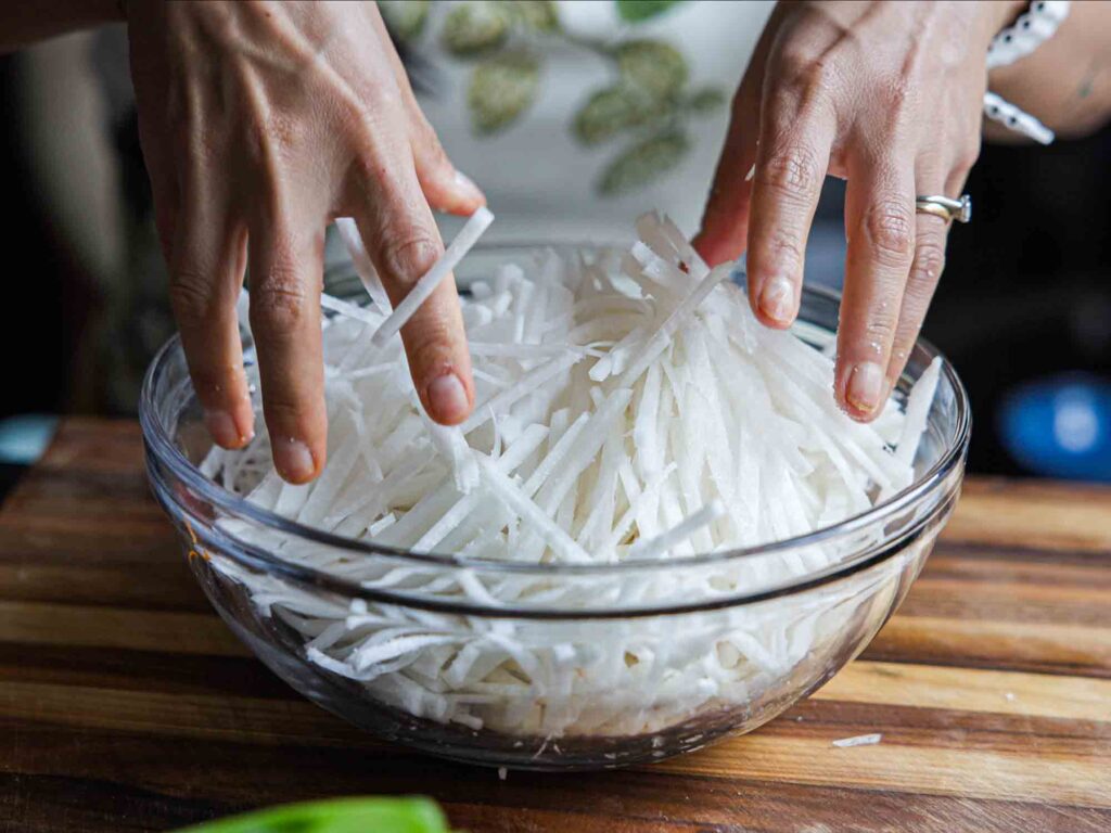 mixing together salt sugar with julienned radish